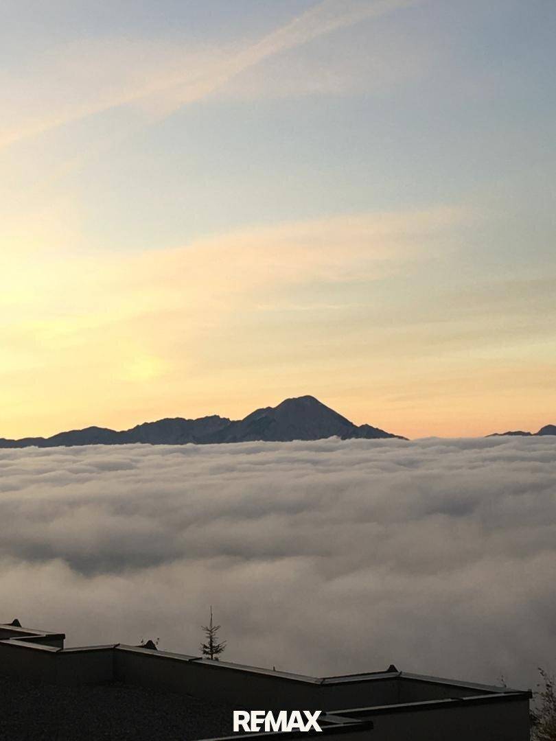 Malerischer Sonnenuntergang über einer Wolkendecke mit Bergsilhouette am Horizont.