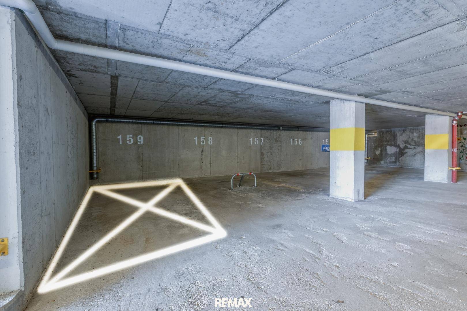Geräumige Tiefgarage mit Betonwänden, nummerierten Stellplätzen und sichtbaren Rohren.