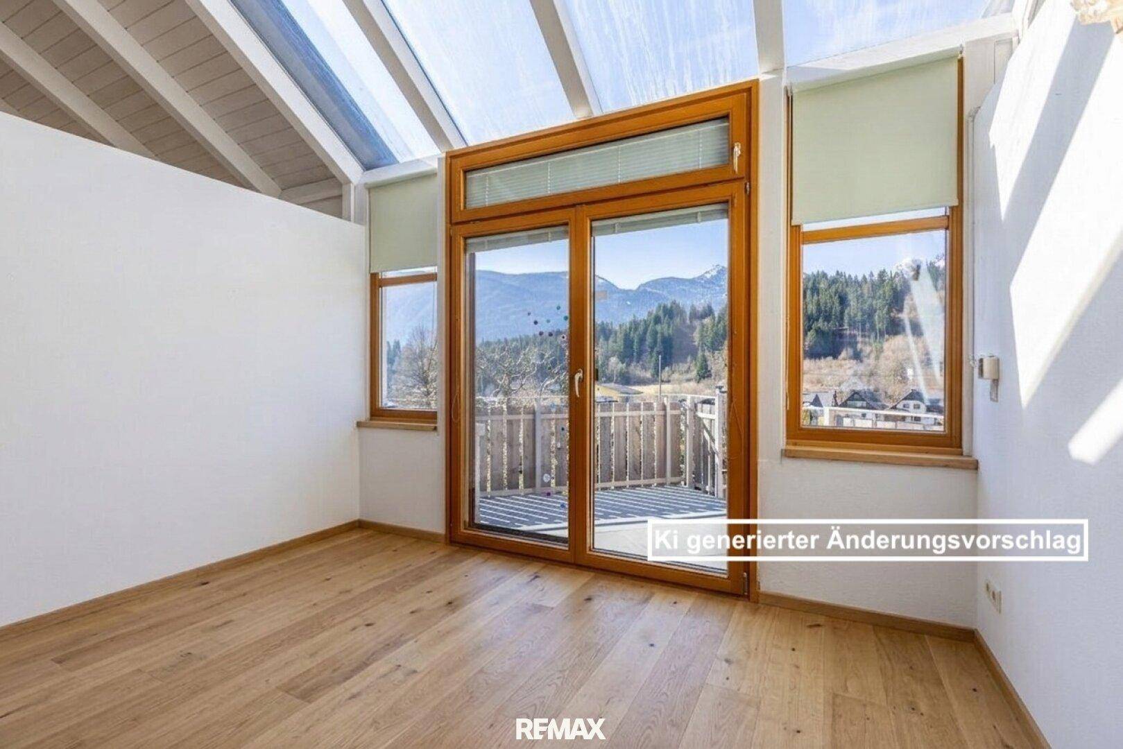 Heller Wintergarten mit Glasdach, Holzboden und Zugang zu einem kleinen Balkon mit Bergblick.