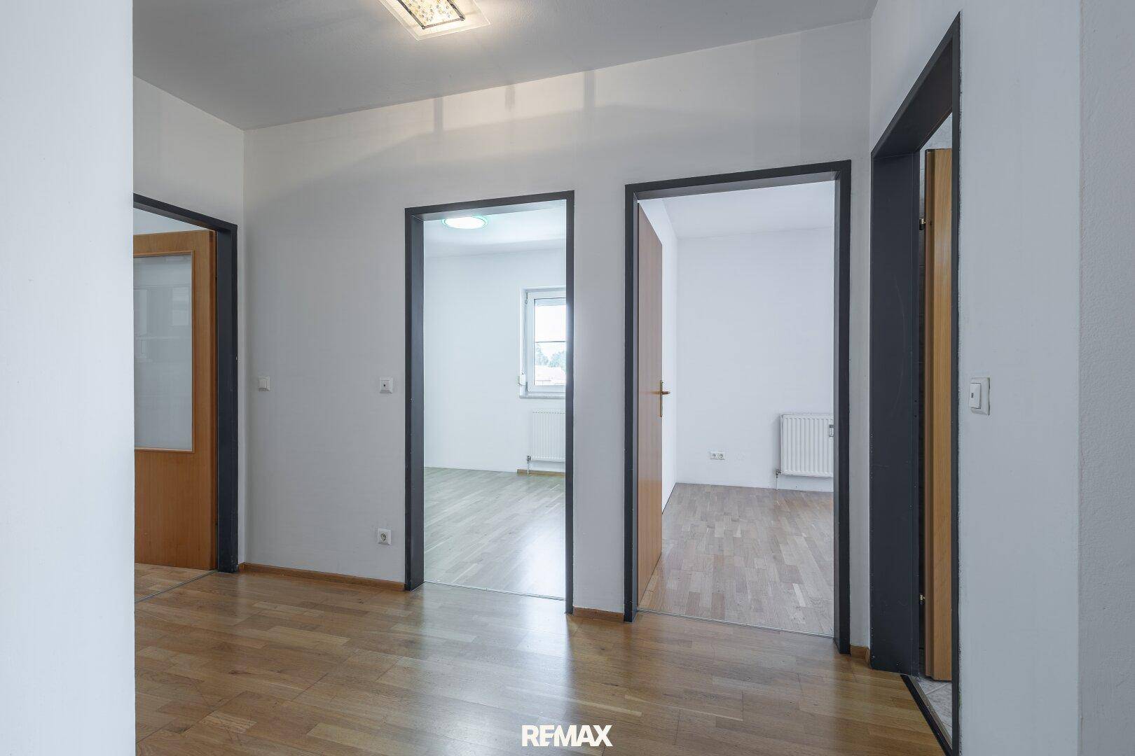 Heller Flur mit Parkettboden und Zugang zu mehreren Zimmern der Wohnung.