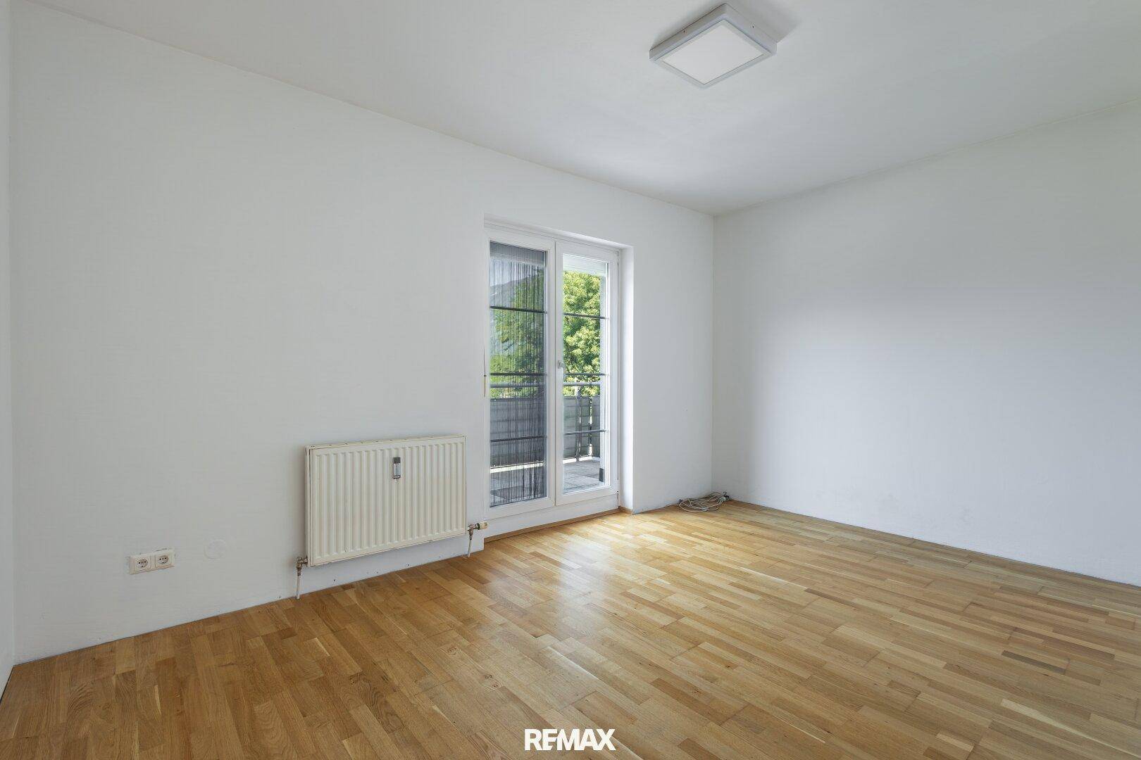 Helles Schlafzimmer mit Parkettboden und Balkonzugang, bereit zur individuellen Gestaltung.