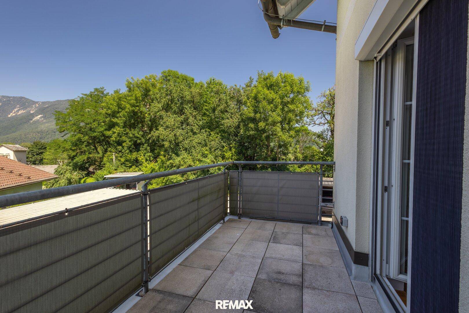 Sonniger Balkon mit weitem Blick ins Grüne und auf die umliegende Landschaft.