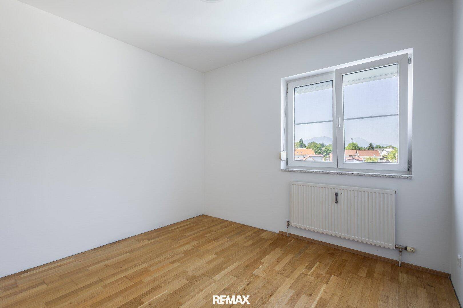 Ruhiges Zimmer mit Parkettboden und Fenster, das viel Tageslicht hereinlässt und Bergblick bietet.
