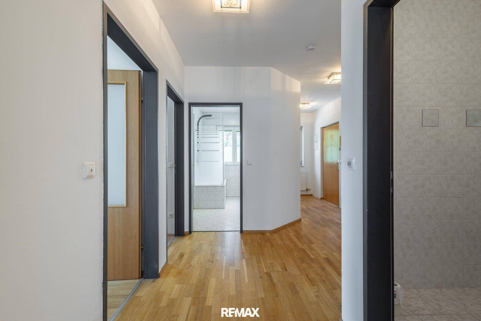 Heller Flur mit Parkettboden, der zu den verschiedenen Räumen der Wohnung führt.