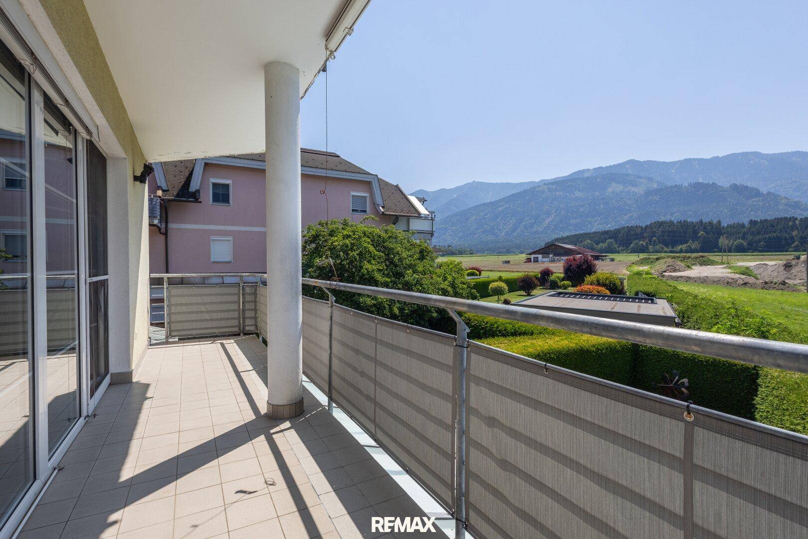 Breiter Balkon mit Fliesenboden und weitem Blick auf die Landschaft und Berge.