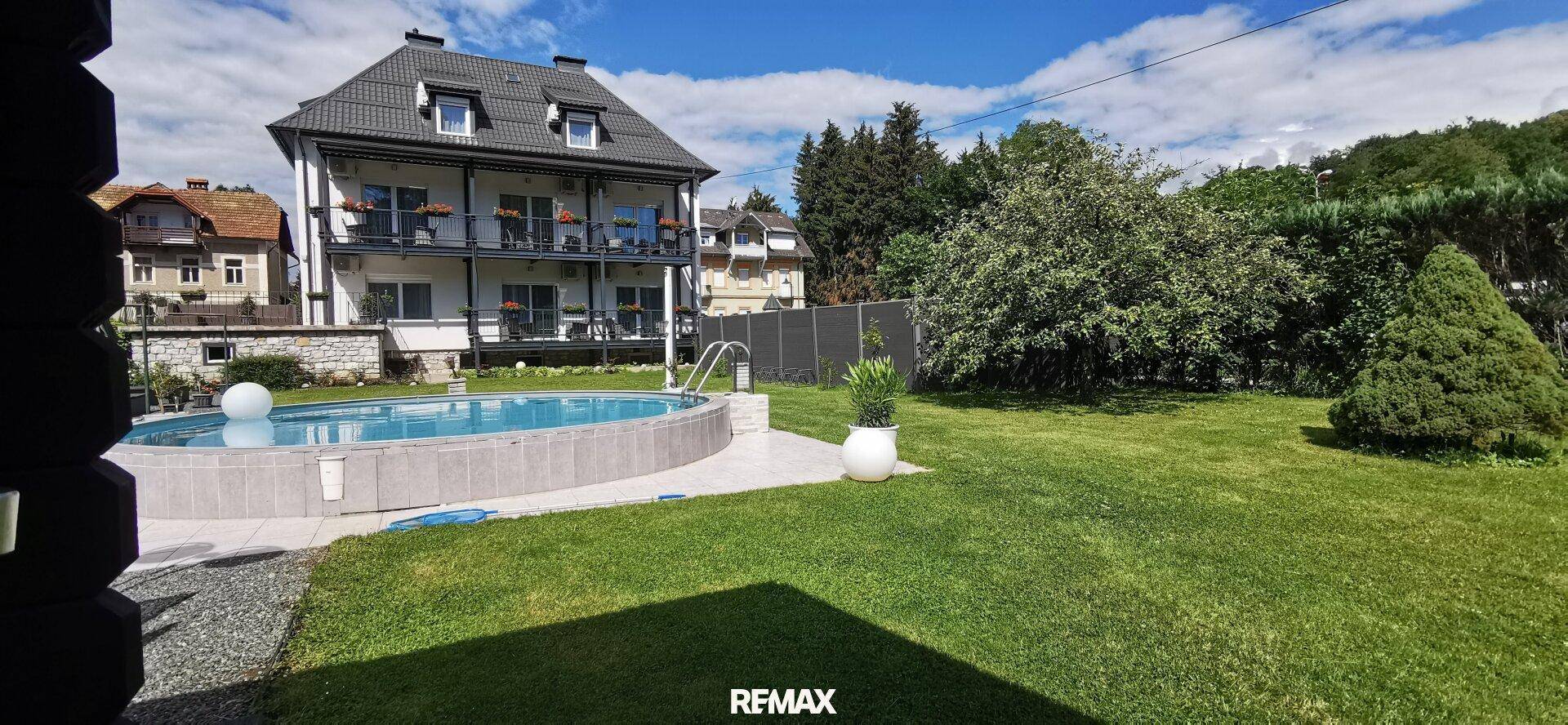 Großer Gartenbereich mit rundem Pool und weitläufiger Rasenfläche vor dem Gebäude.