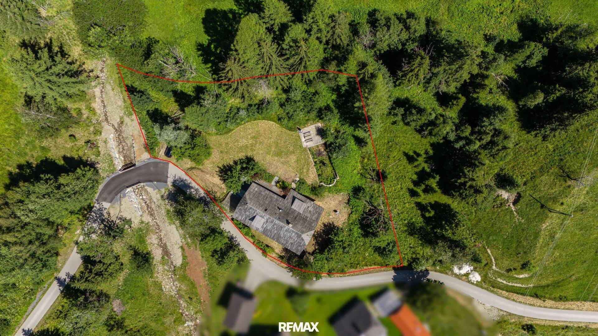Luftaufnahme des Grundstücks mit eingezeichneter Grenze, umgeben von Wald und Wiesen.