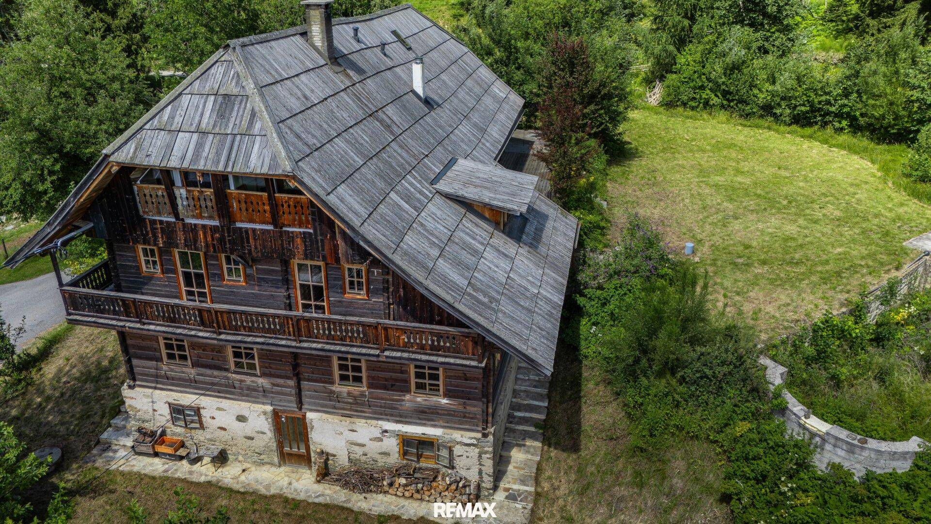 Detailansicht der traditionellen Holzfassade des Hauses mit Balkon und Steinsockel.
