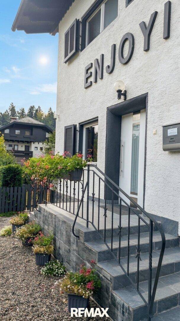 Eingangsbereich eines Hauses mit Treppe, Geländer und dekorativen Blumenkästen.