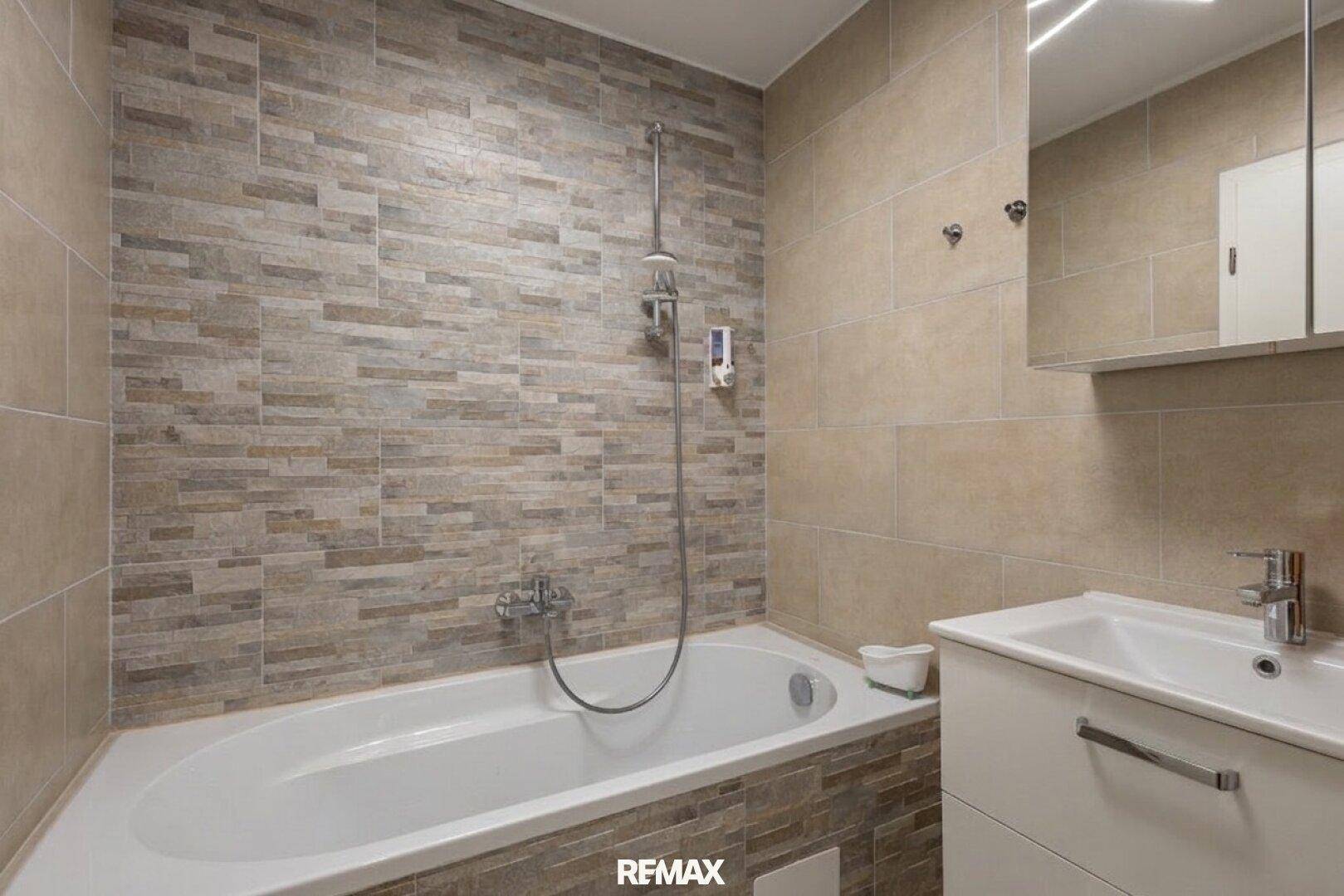Modern gefliestes Badezimmer mit Badewanne und integrierter Dusche sowie einem Waschbeckenunterschrank.
