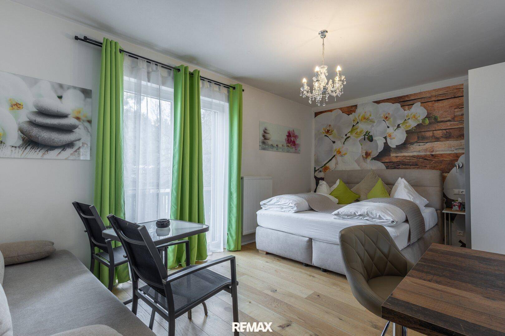 Helles Schlafzimmer mit Doppelbett, Sofa und kleinem Esstisch.