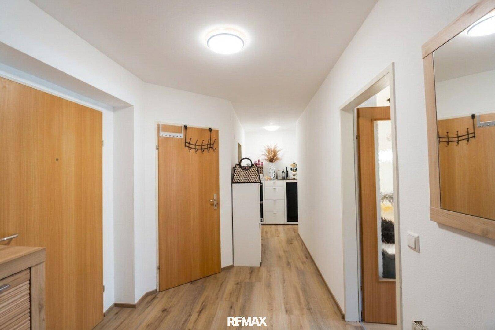 Heller Flur mit Laminatboden und Holztüren, der zu weiteren Räumen führt.
