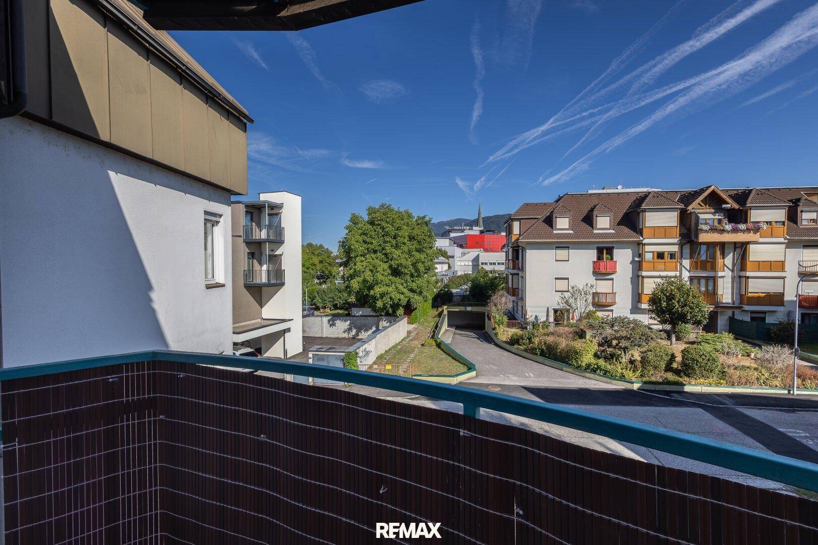 Blick vom Balkon auf die umliegende Wohngegend mit Häusern und Bäumen.