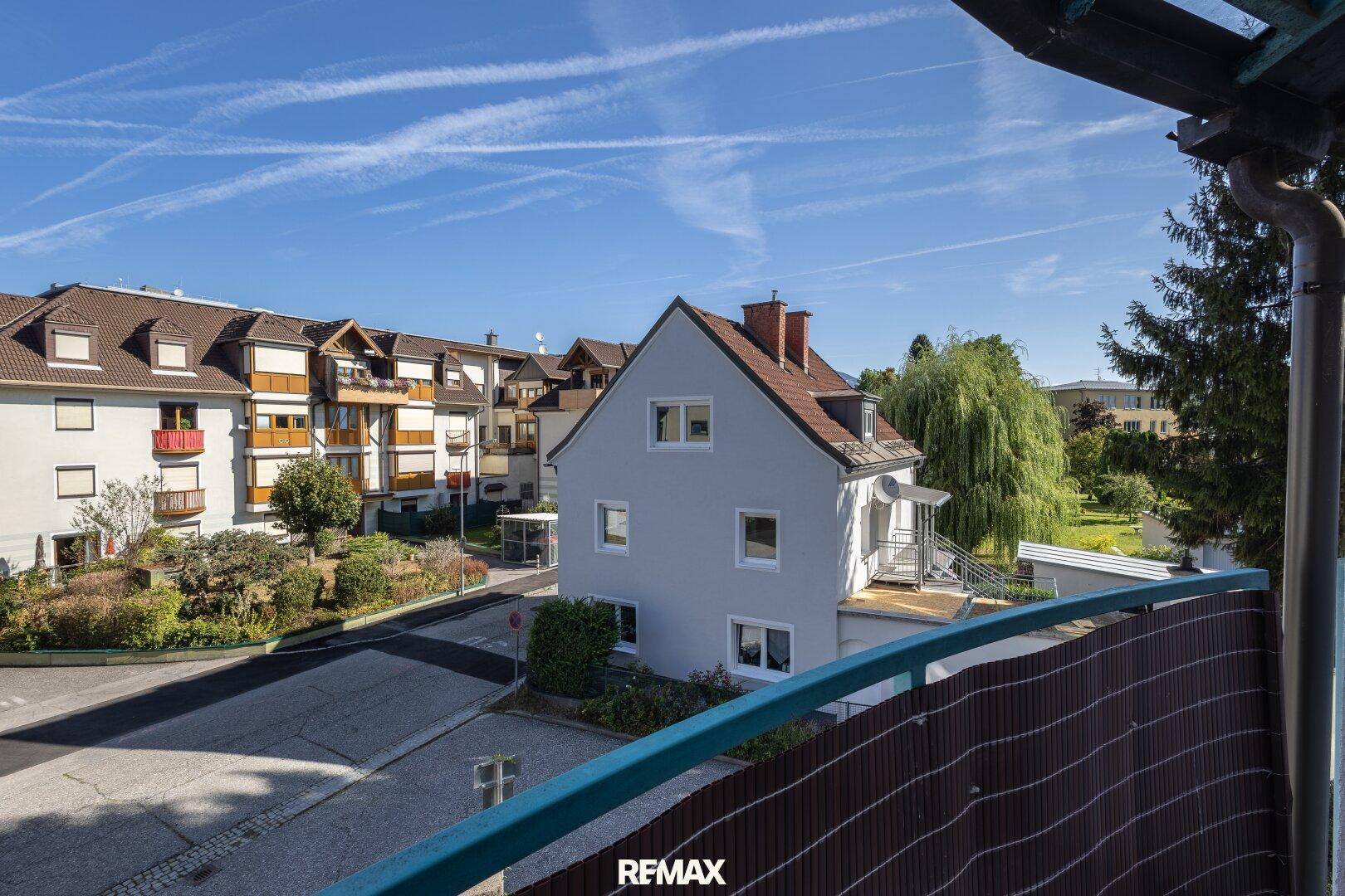 Panoramablick vom Balkon auf die Wohnsiedlung und die grüne Umgebung unter blauem Himmel.