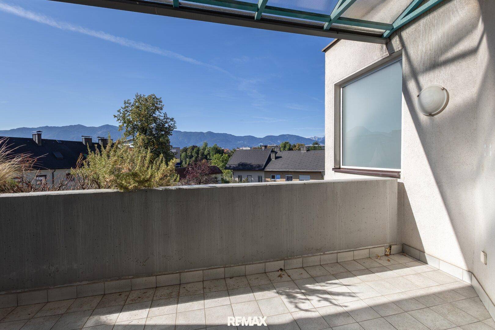 Sonniger Balkon mit Fliesenboden und weitem Blick auf die Berge und die Umgebung.