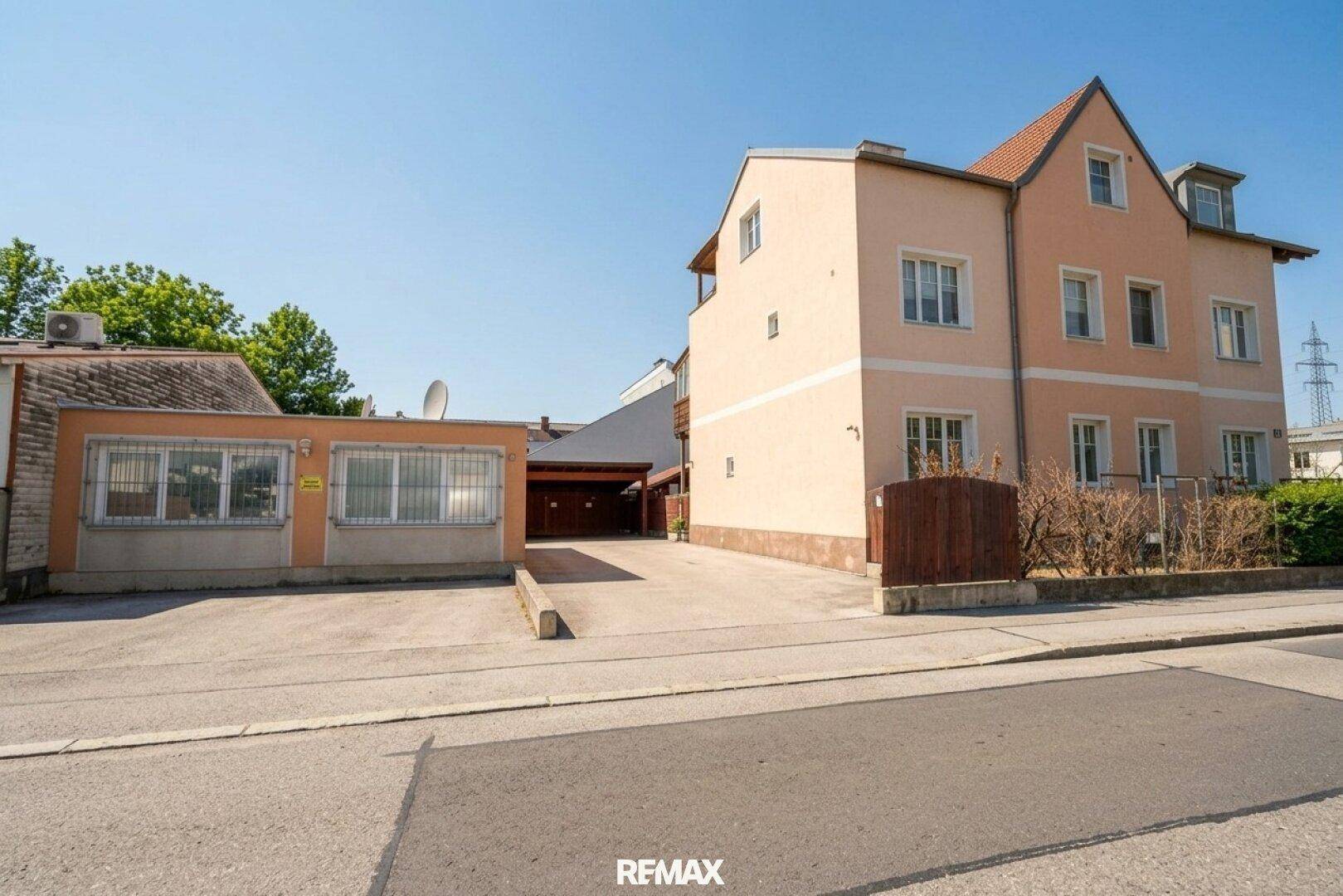 Gesamtansicht des Wohnhauses von der Straße, mit Nebengebäude und gepflasterter Zufahrt.