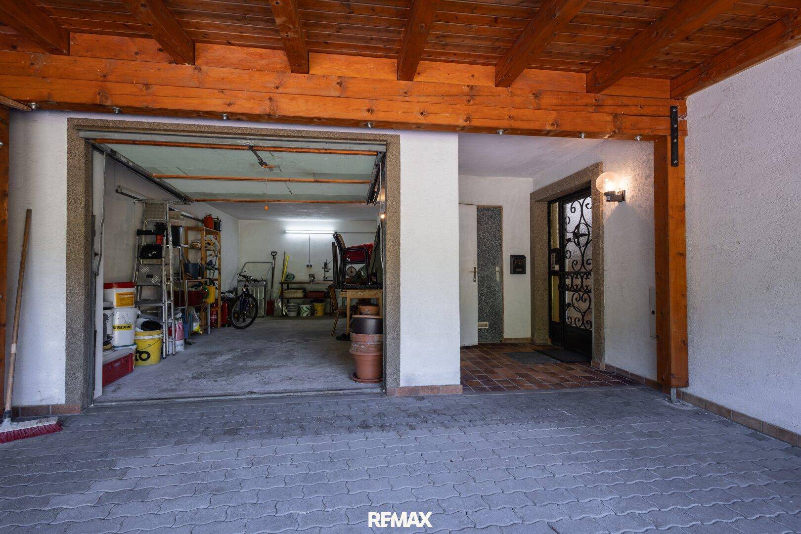 Überdachter Carport-Bereich mit Zugang zu einer Werkstatt oder Garage und dem Hauseingang.