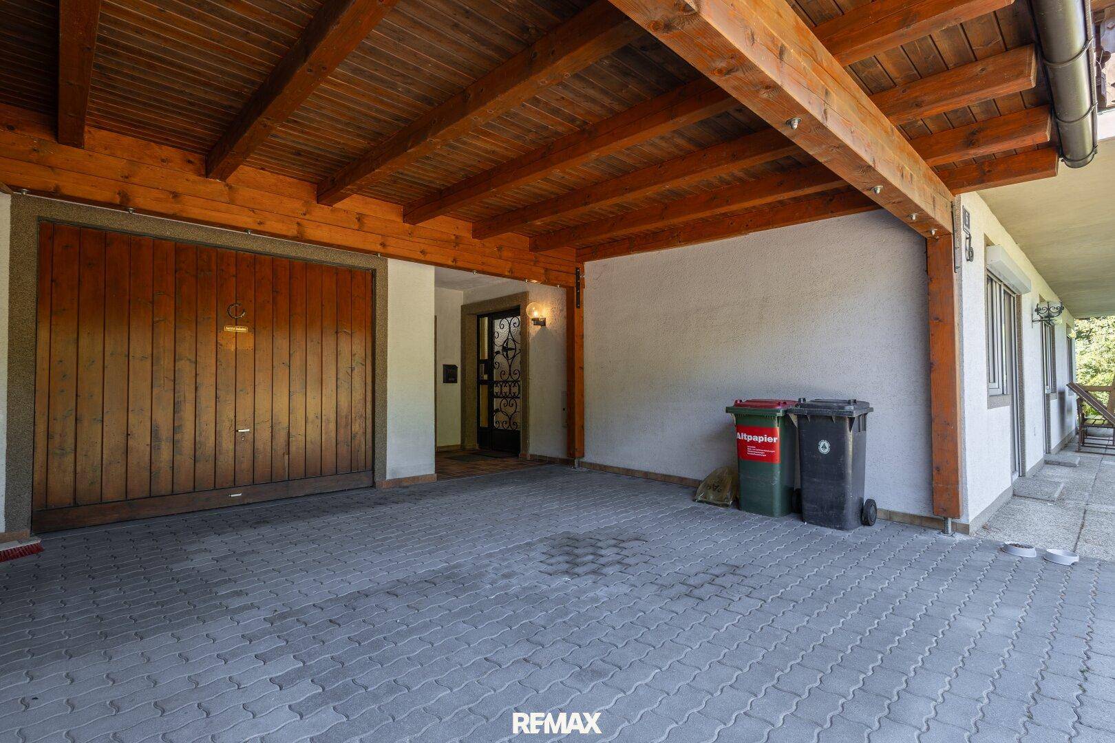 Geräumiger überdachter Carport mit Holzbalken und Zugang zum Hauseingang.