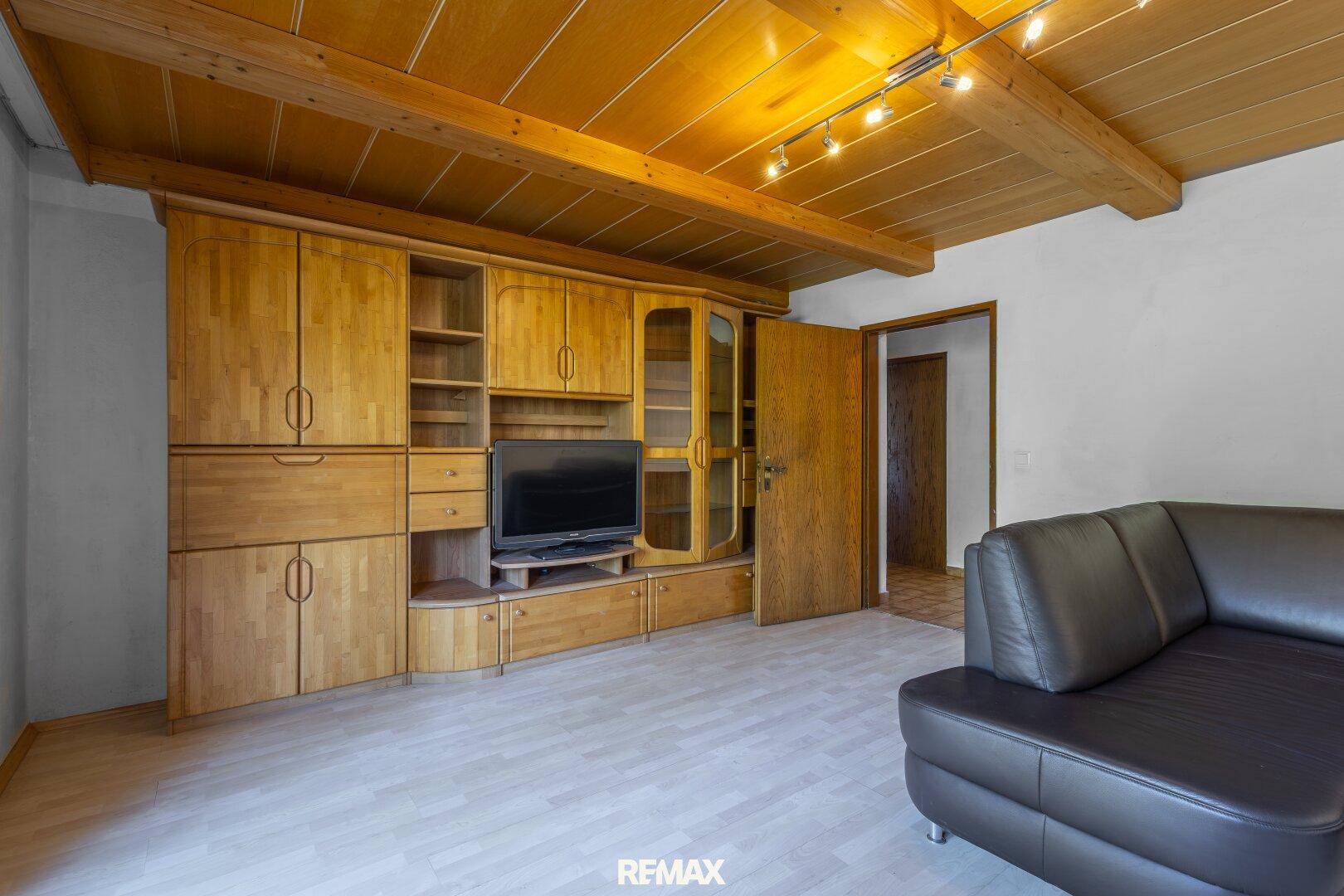 Gemütliches Wohnzimmer mit Holzbalkendecke, hellem Laminatboden und traditionellen Holzmöbeln.