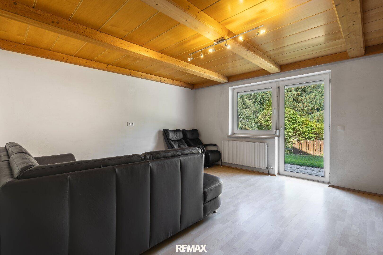 Helles Wohnzimmer mit Holzbalkendecke, Laminatboden und direktem Zugang zum Garten.