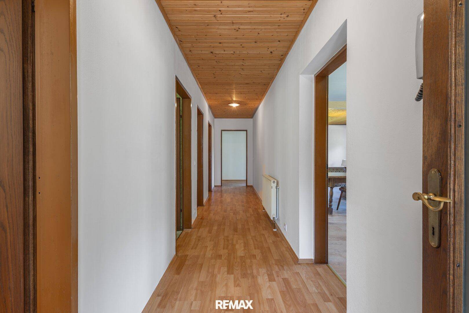 Heller Flur mit Holzdecke und Laminatboden, der zu verschiedenen Wohnbereichen führt.