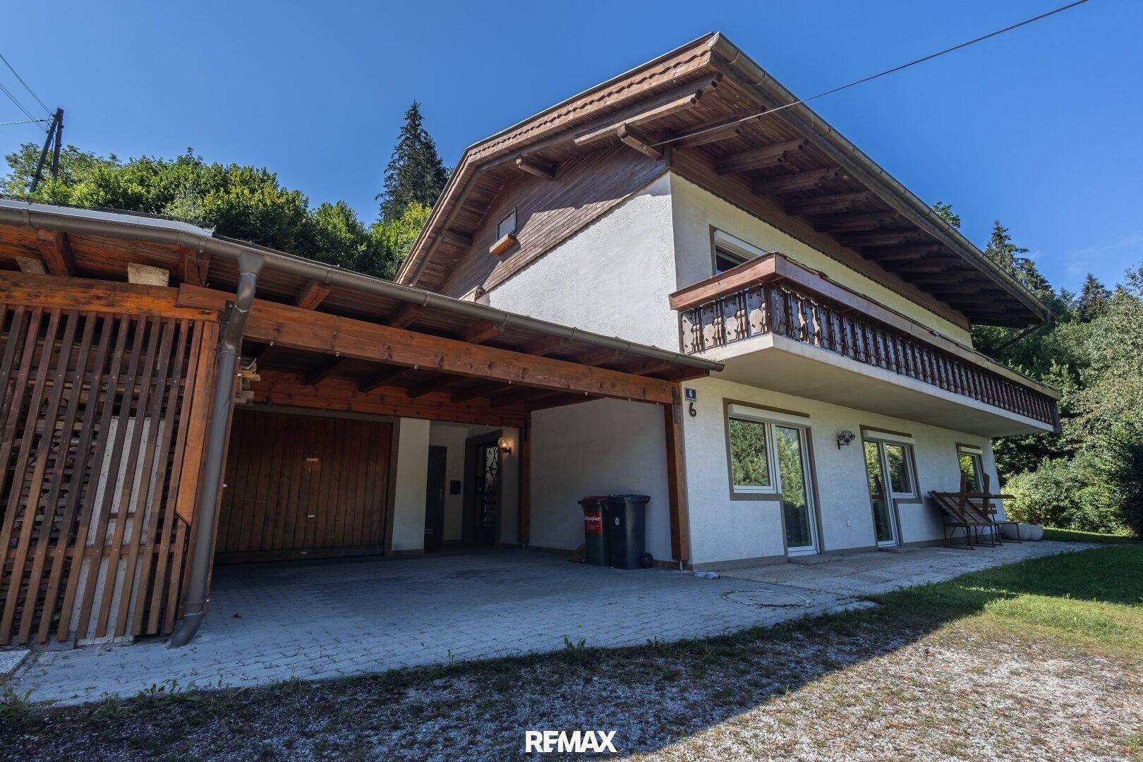 Traditionelles Haus mit Carport, Balkon und umgebender Natur in ländlicher Umgebung.