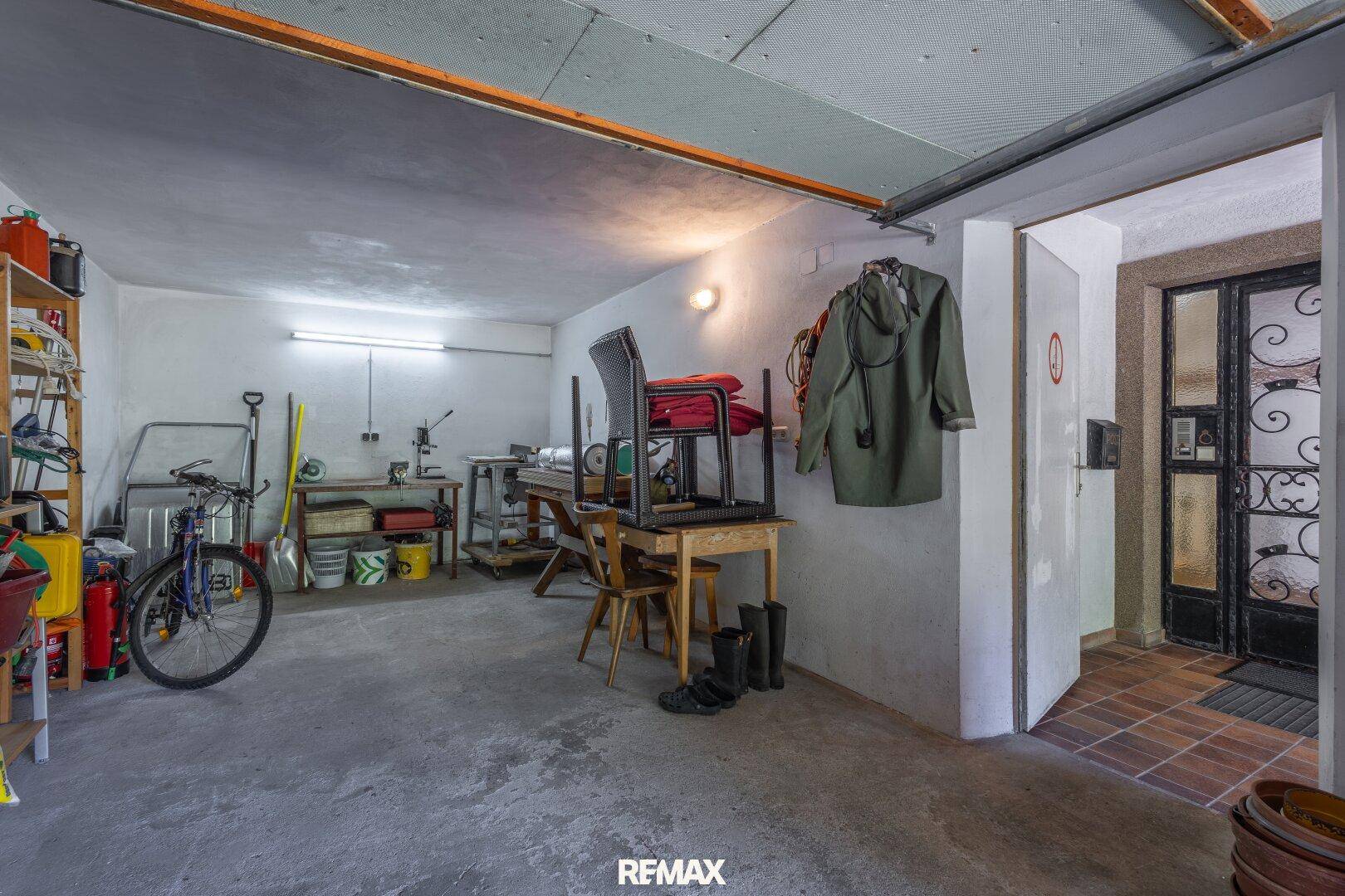 Geräumige Garage mit Werkstattbereich, Betonboden und Stauraum für Fahrräder und Werkzeuge.