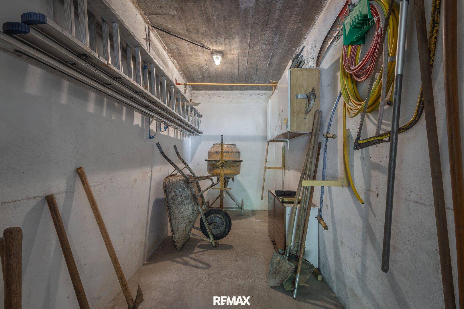 Praktischer Abstellraum im Keller mit Betonboden, Leitern und Gartengeräten für vielfältige Nutzung.