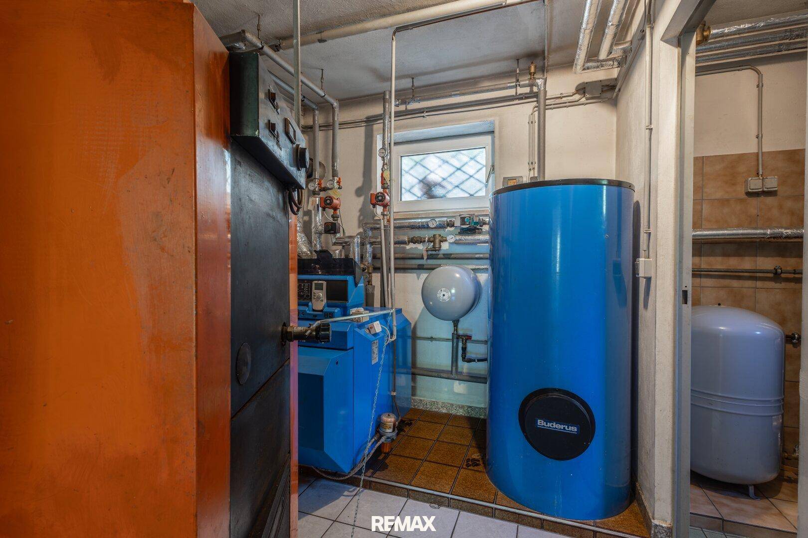 Heizungsraum mit Buderus-Anlage, Warmwasserspeicher und zahlreichen Rohren für die Haustechnik.