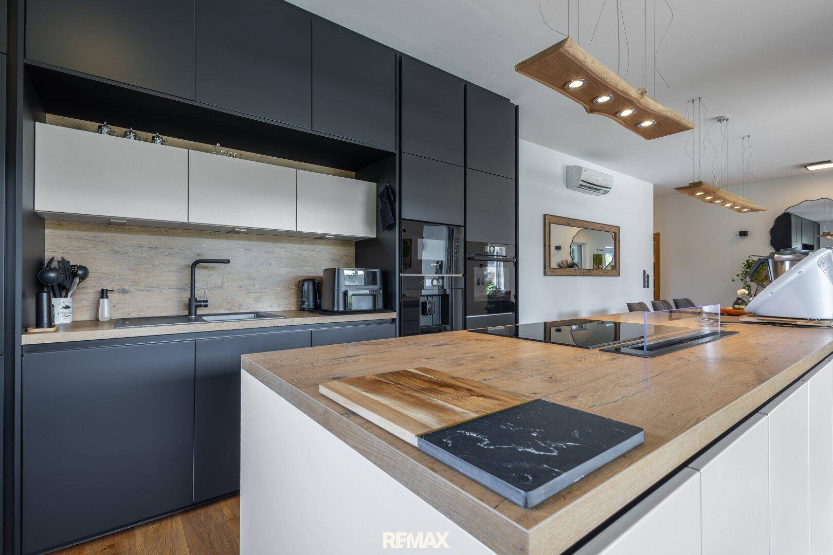Moderne Küche mit dunklen Schränken, Holz-Arbeitsplatte und integrierten Geräten.