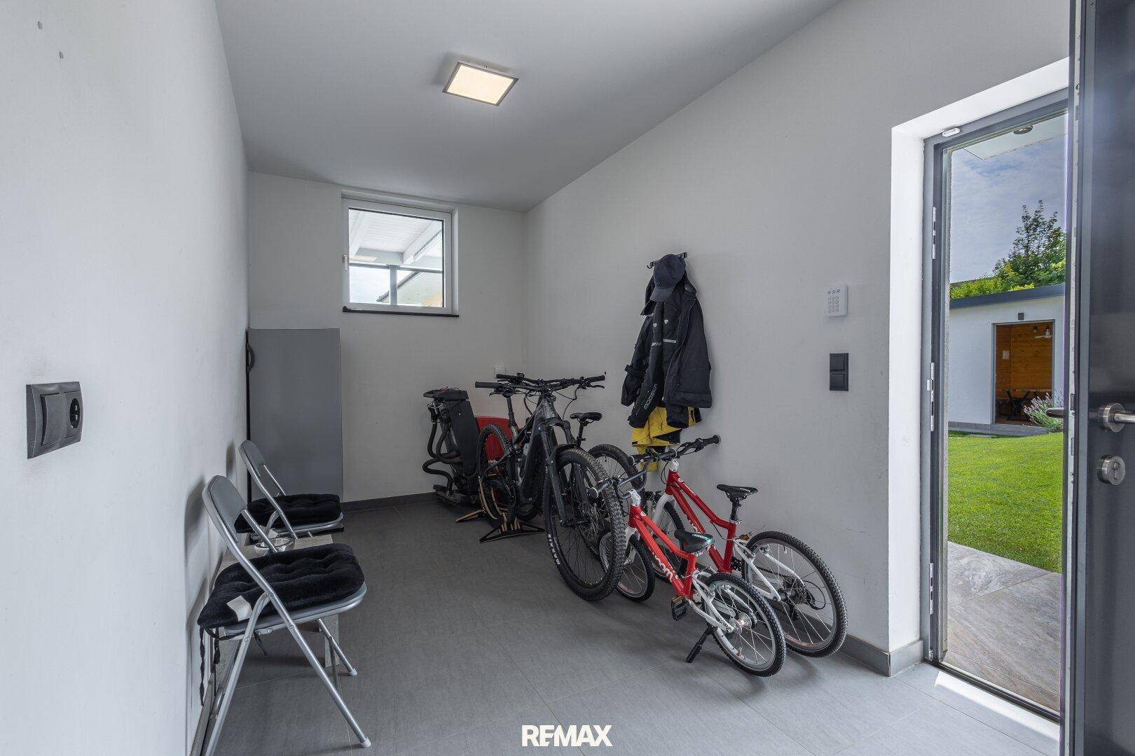 Praktischer Abstellraum mit Fahrrädern, Fenster und direktem Zugang zum Außenbereich.