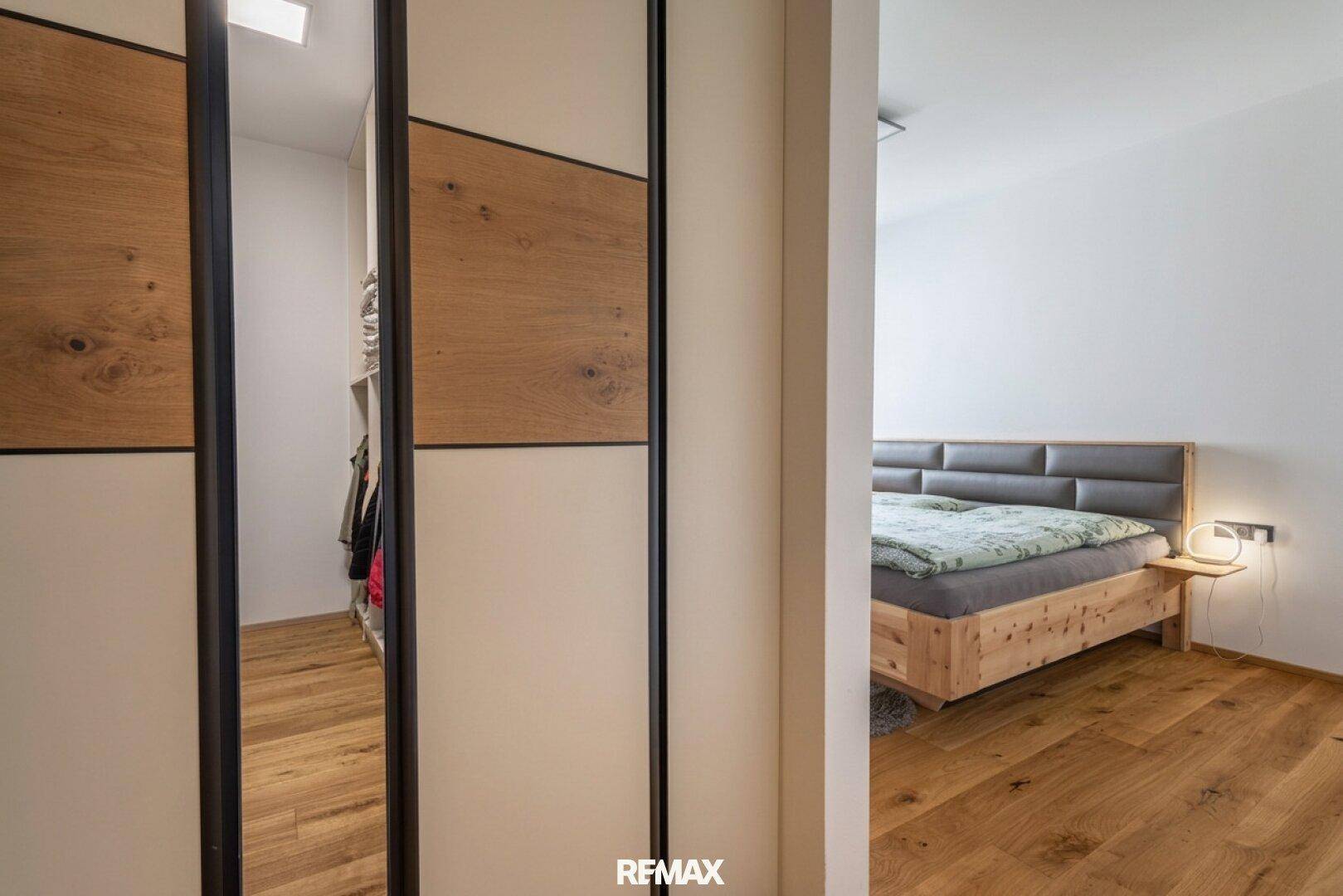 Schlafzimmer mit Holzboden und Zugang zu einem begehbaren Kleiderschrank.