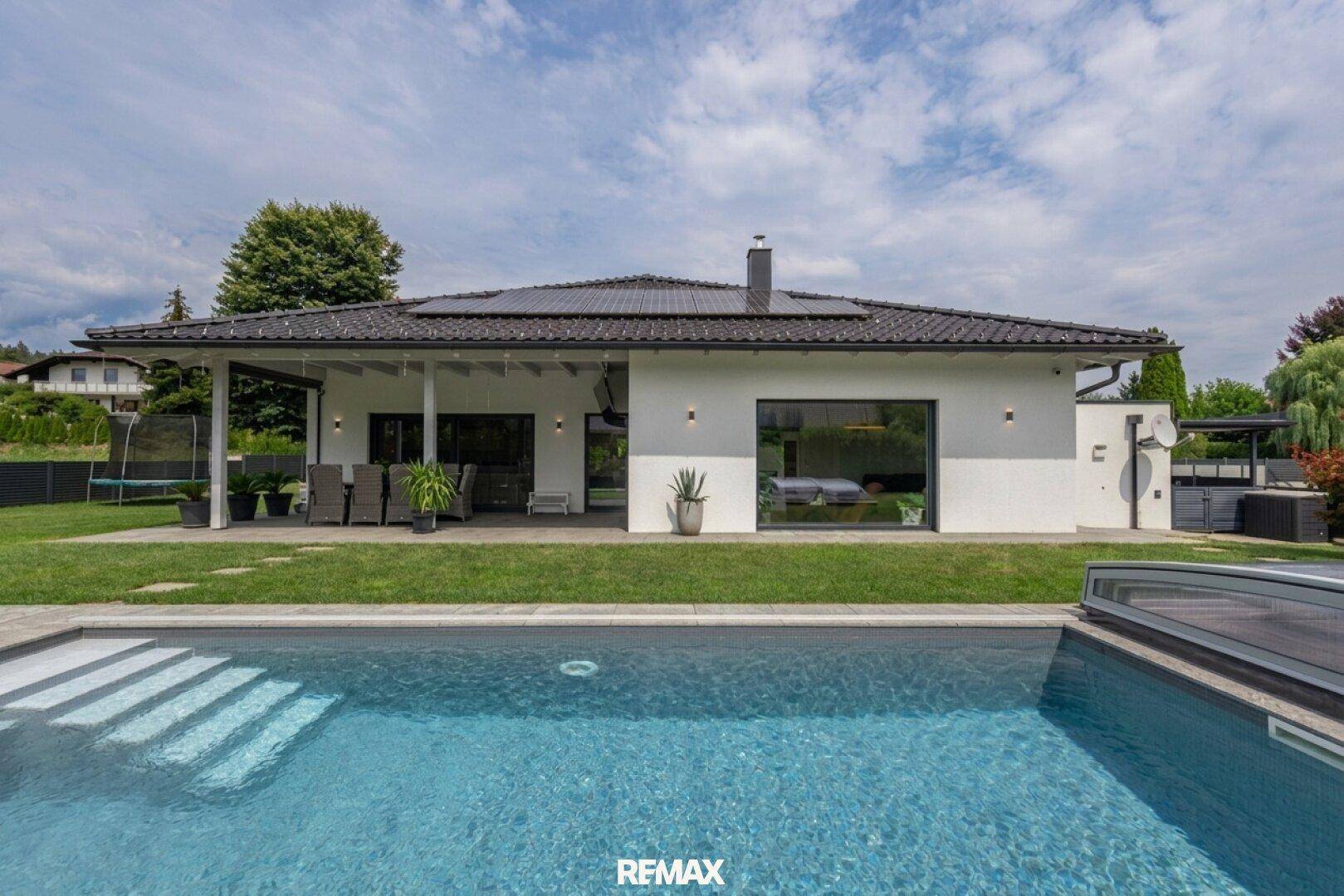 Modernes Haus mit großem Garten, Swimmingpool und überdachter Terrasse, ideal für Entspannung im Freien.