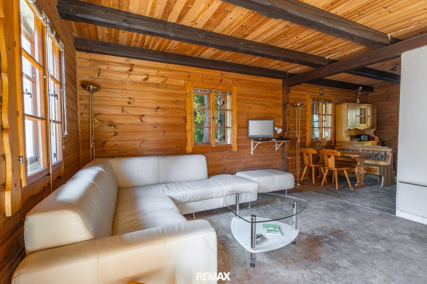 Geräumiger Wohnbereich mit Holzwänden, Deckenbalken und separatem Essbereich.