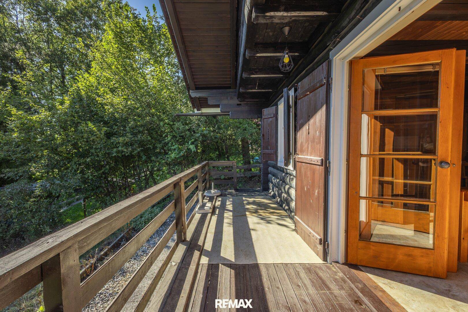 Holzbalcon mit Geländer und Blick auf die umliegende grüne Landschaft.