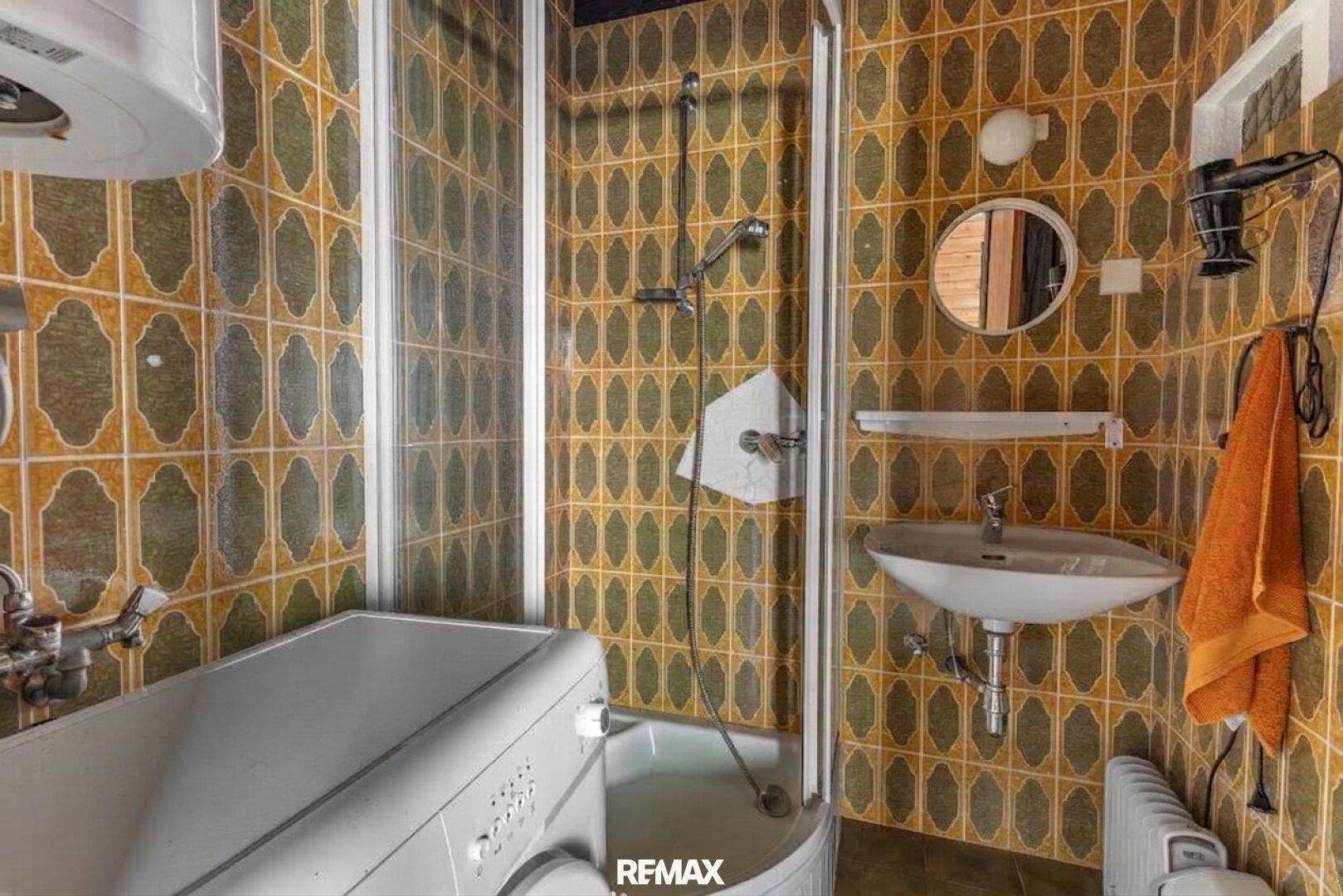 Badezimmer mit Duschkabine, Waschbecken und auffälligen gemusterten Fliesen.