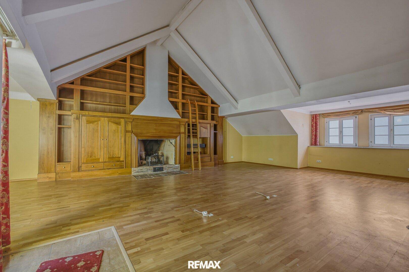Geräumiges Wohnzimmer mit Holzboden, Kamin und hohen Decken, ideal für große Familien.