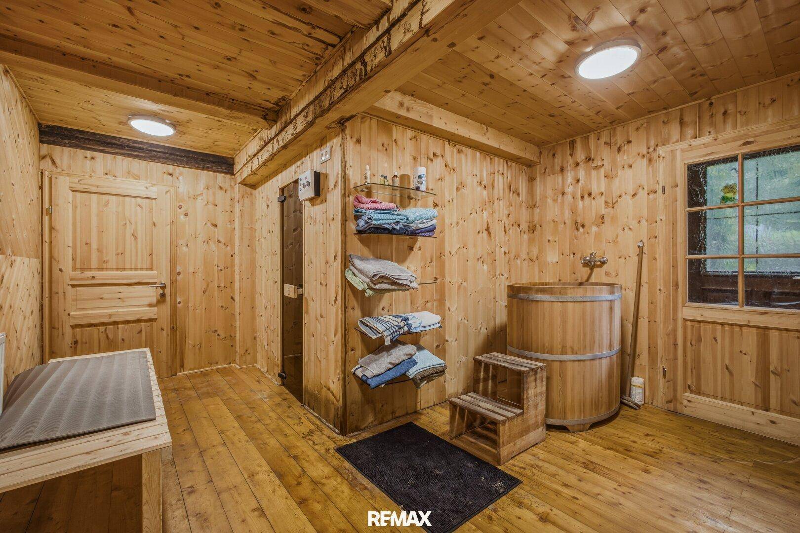 Rustikaler Raum mit Holzwänden, Holzboden und einem großen Holzbottich.