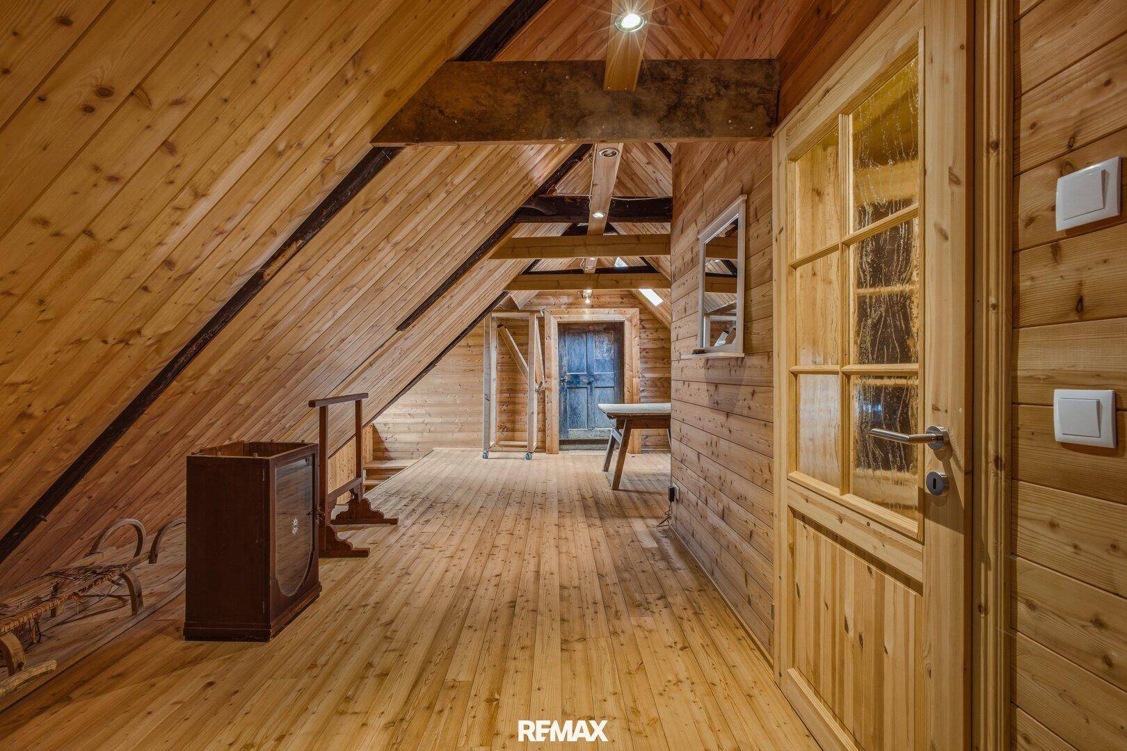 Ausgebauter Dachboden mit Holzboden, Holzwänden und sichtbaren Dachbalken.