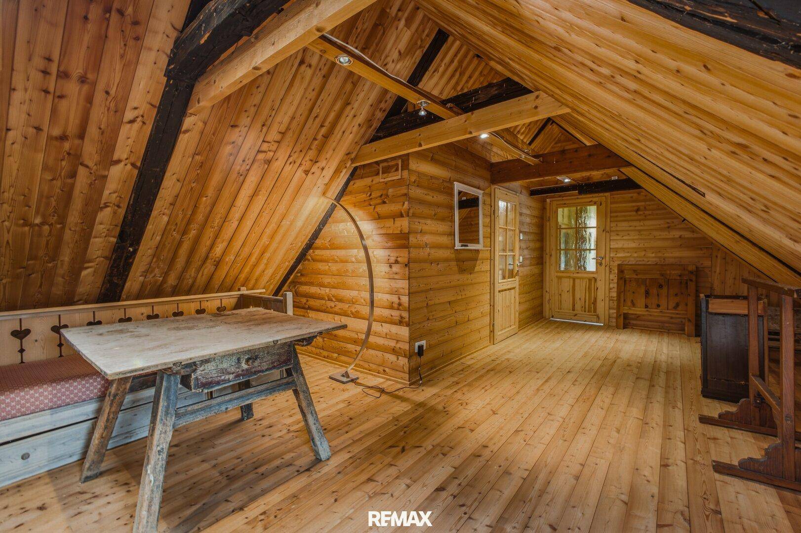 Geräumiger Dachboden mit Holzboden, Holzwänden und rustikalen Möbeln.