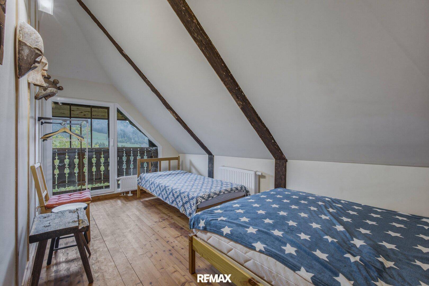 Schlafzimmer im Dachgeschoss mit Holzboden, Dachschrägen und Balkonzugang.