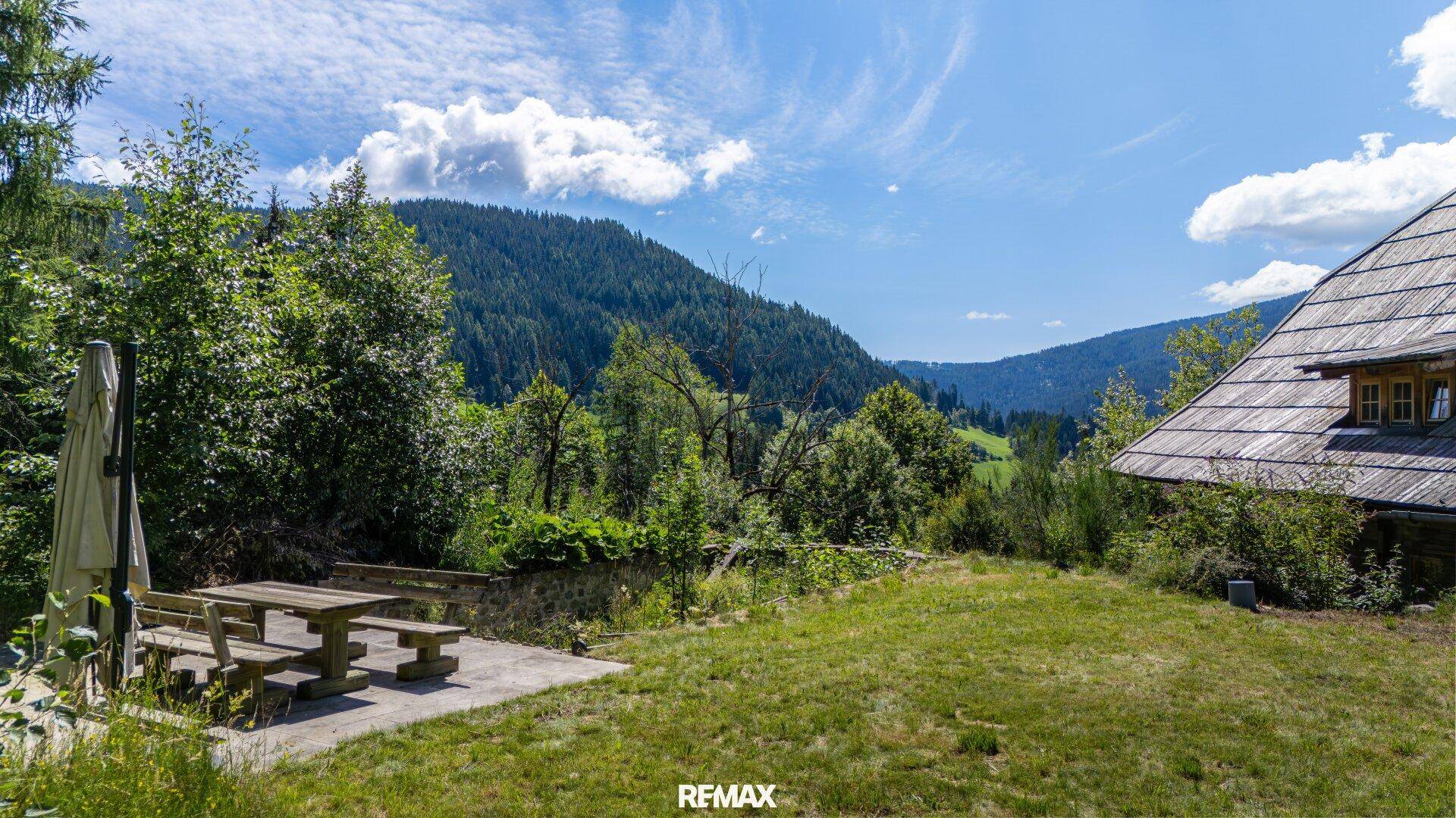 Großer Gartenbereich mit Rasenfläche und Picknicktisch, bietet einen weiten Blick auf die umliegenden Berge.