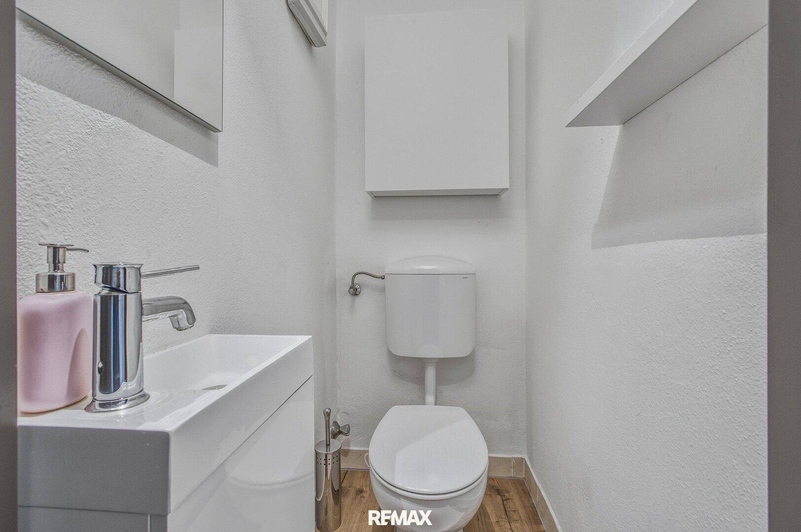 Modernes Gäste-WC mit wandhängendem WC und kleinem Waschbecken.