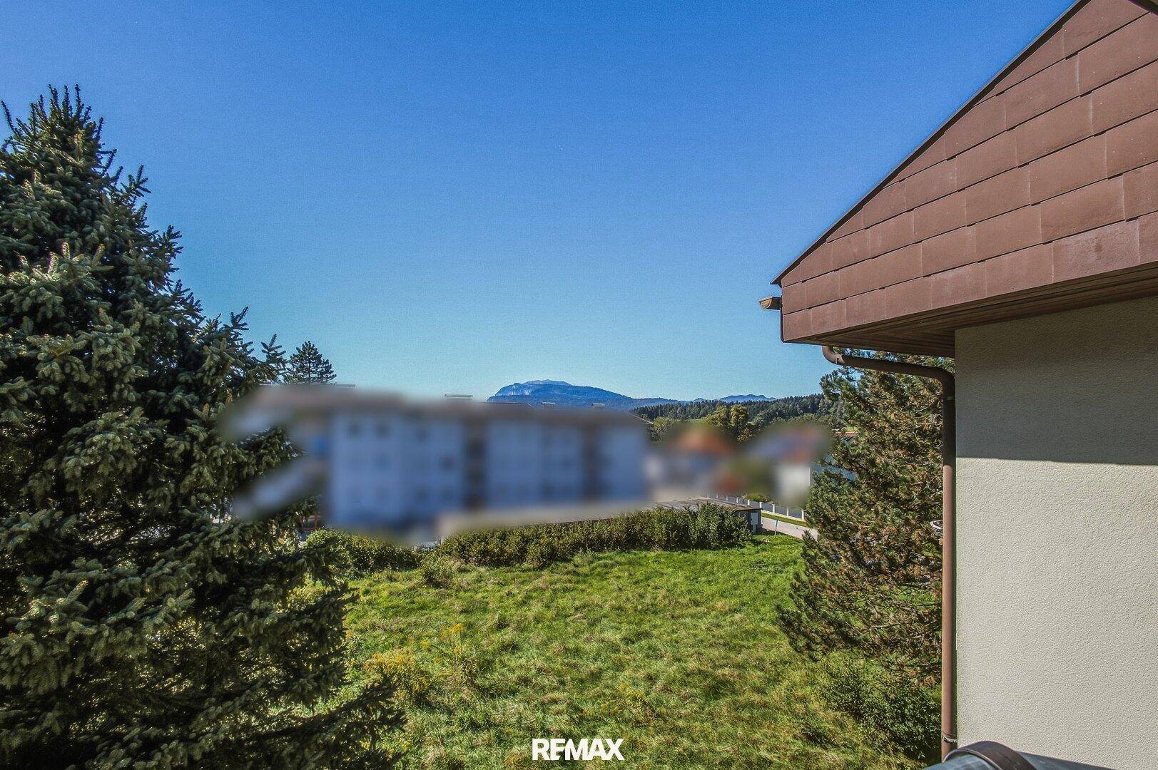 Weitläufiger Ausblick vom Balkon auf die grüne Umgebung und ferne Berge.
