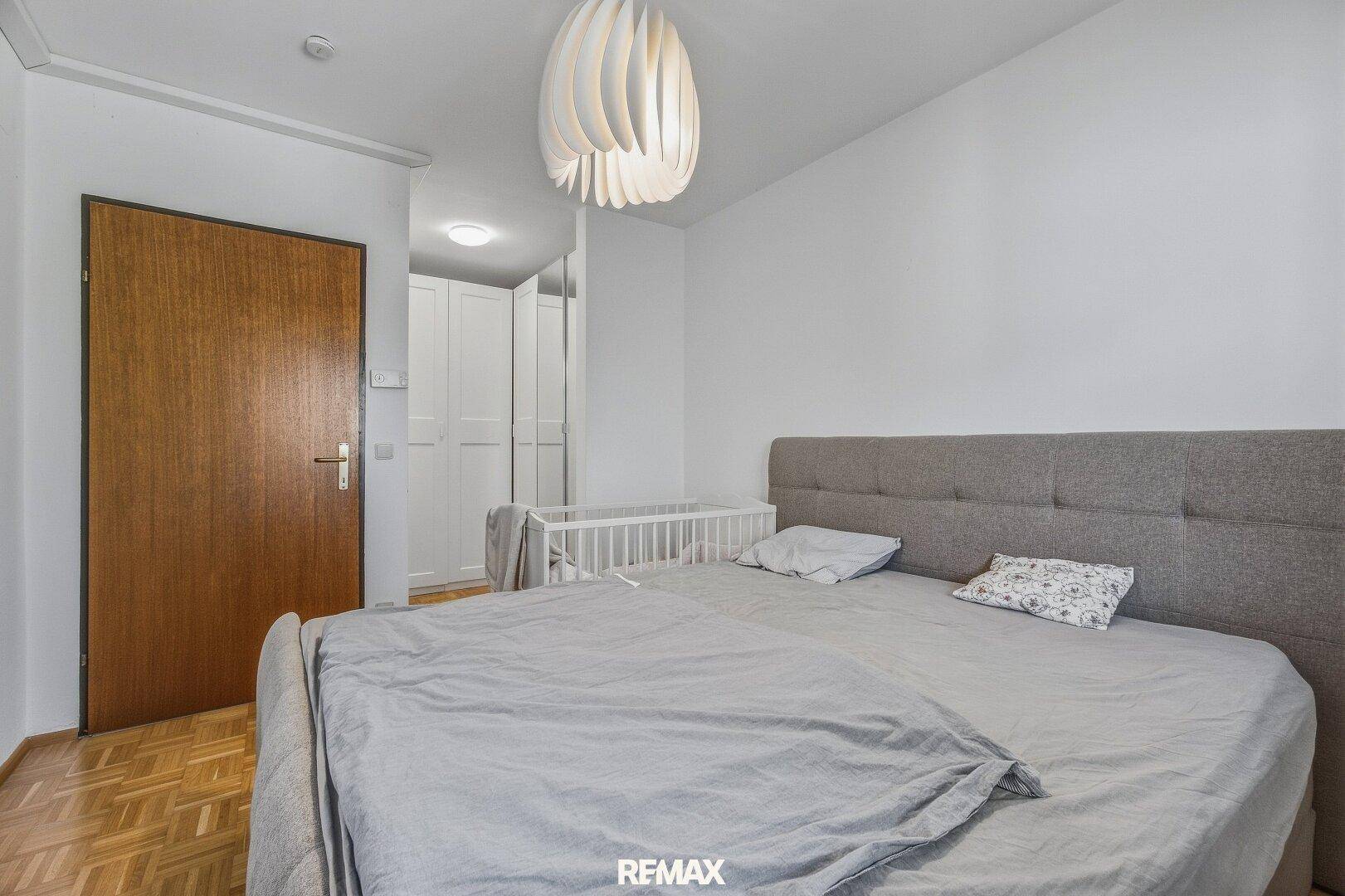 Schlafzimmer mit Doppelbett, Parkettboden und weißem Kleiderschrank.