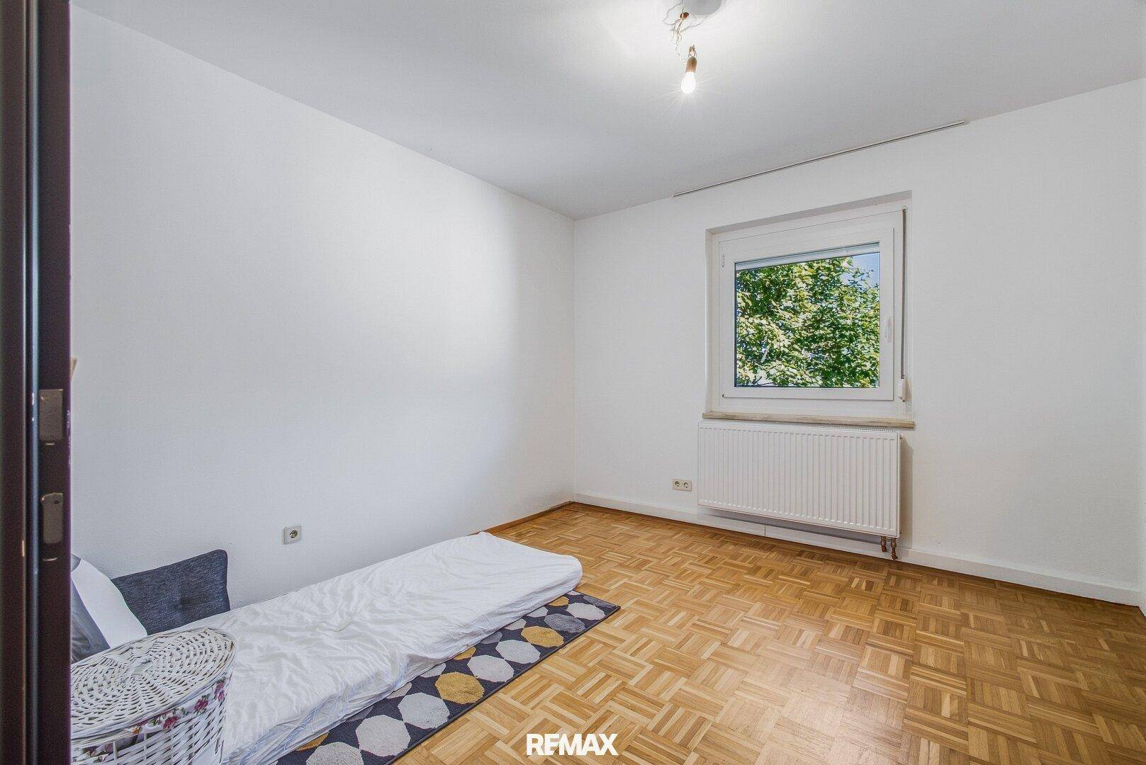 Kinderzimmer oder Gästezimmer mit Parkettboden und Fenster zum Garten.