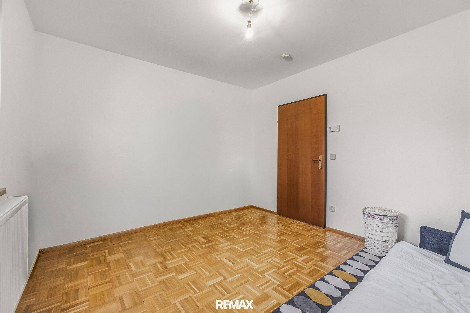 Geräumiges Zimmer mit Parkettboden und Holztür, ideal als Kinderzimmer.