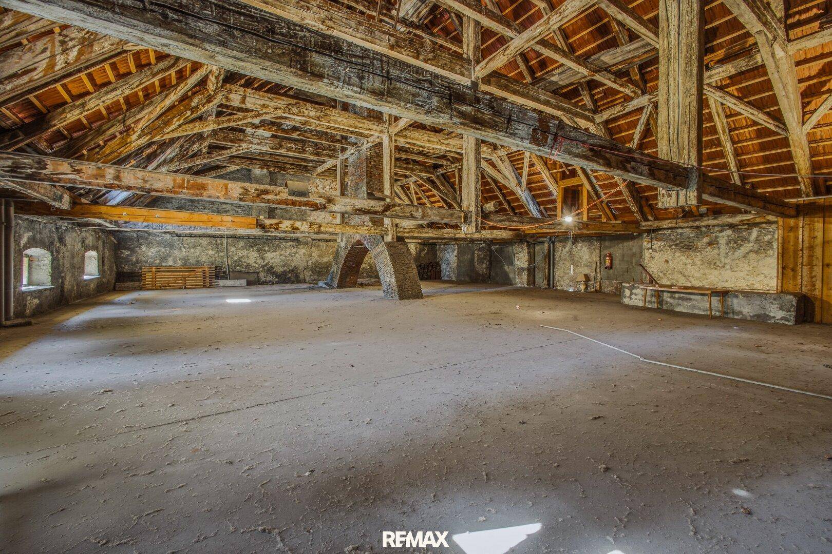 Geräumiger, ungenutzter Dachboden mit sichtbaren Holzbalken und robustem Betonboden.