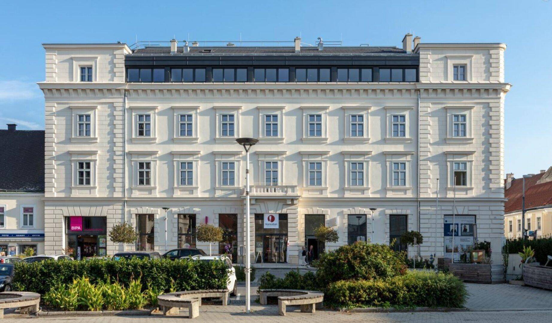 Historisches Gebäude mit klassischer Fassade und modernem Dachausbau in der Stadt.