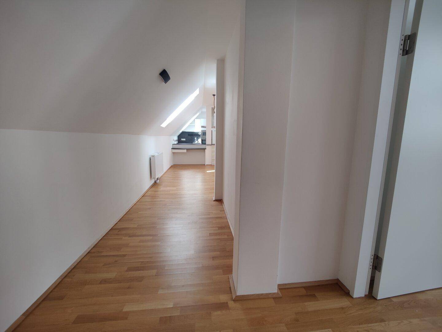 Heller Flur mit Parkettboden und Dachschrägen, der zu weiteren Räumen führt.